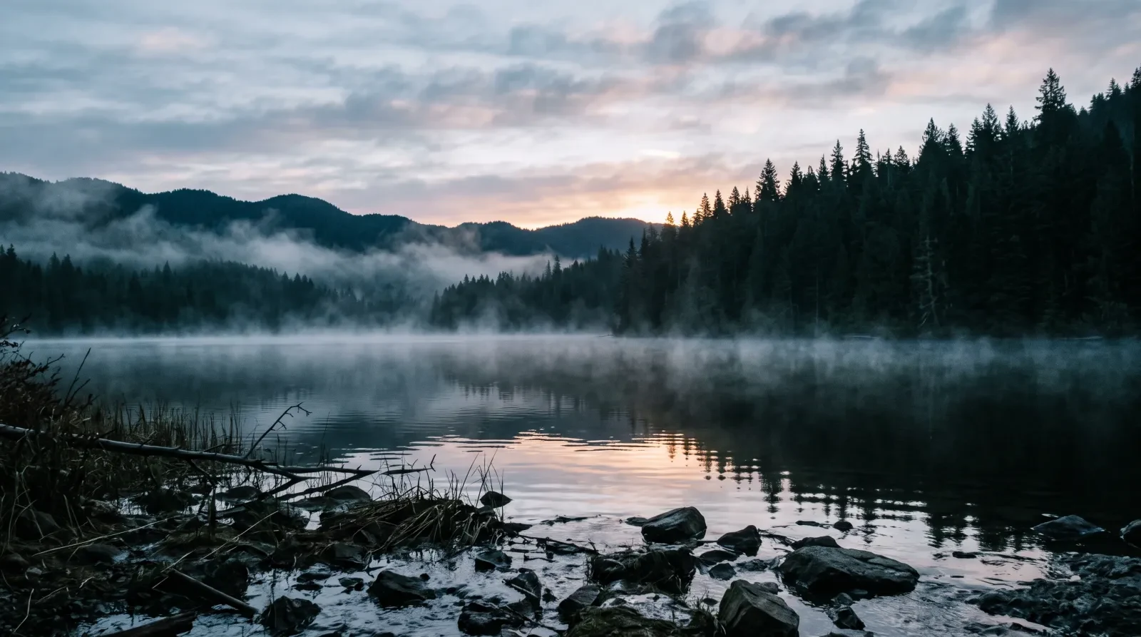 A cold lake at sunrise with mist lifting off the water